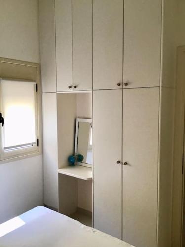 a bedroom with white cabinets and a mirror at Sea Breeze - Home with a View in Bouzéïka