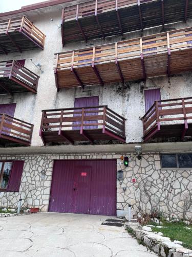 un edificio con puertas moradas y balcones de madera. en Beta terminillo, en Terminillo