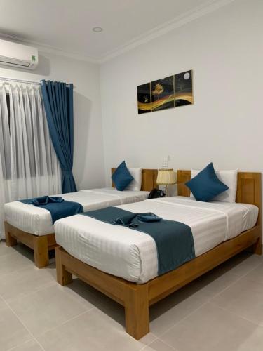 twee bedden in een kamer met blauwe kussens bij HA ANH PHAN THIẾT HOTEL in Phan Thiet