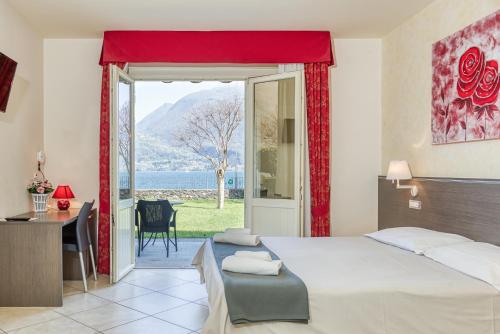 a bedroom with a bed and a desk and a window at Hotel Lumin in Cremia