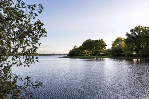 a view of a large lake with trees on the shore at Best Western Plus Le Roi Arthur Hôtel & Spa in Ploërmel