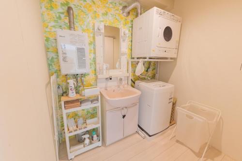 uma pequena casa de banho com um lavatório e uma máquina de lavar roupa em million pointz em Amami