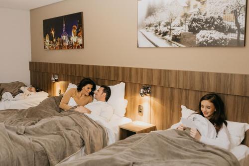 a group of three people laying in beds at Hotel Fioreze Centro in Gramado