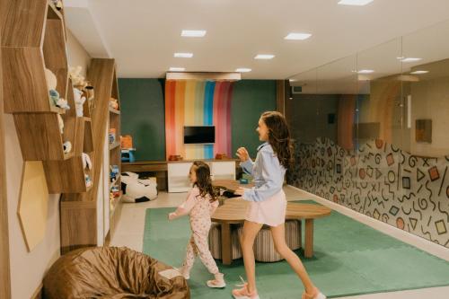 a woman and a little girl walking through a room at Hotel Fioreze Centro in Gramado