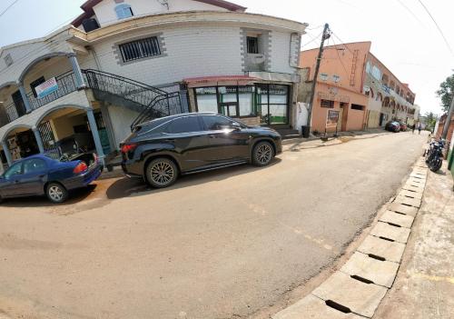 un par de autos estacionados frente a una casa en The Yafé Bastos 7, en Yaoundé