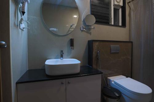 a bathroom with a sink and a mirror and a toilet at HOTEL BLUEMOON in Tirunelveli