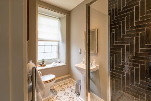 a bathroom with a toilet and a sink and a staircase at The George Inn & Plaine in Norton Saint Philip