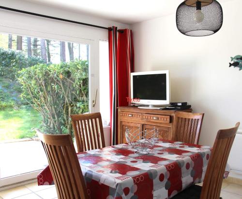 a dining room with a table and a television at APPARTEMENT LES PINS PENCHES Hardelot plage in Neufchâtel-Hardelot