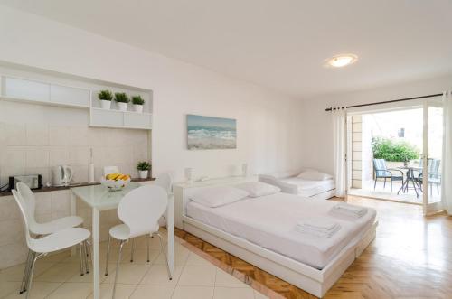 1 dormitorio blanco con 1 cama, mesa y sillas en House Apartments Ariva, en Dubrovnik