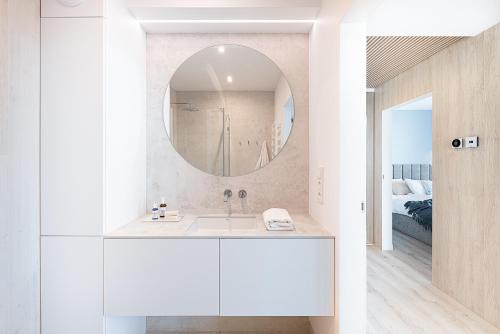 a white bathroom with a sink and a mirror at Apartament Morskie Widoki in Darłówko
