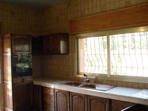 a kitchen with wooden cabinets and a sink and a window at VILLA PLAISANCE in Meknès