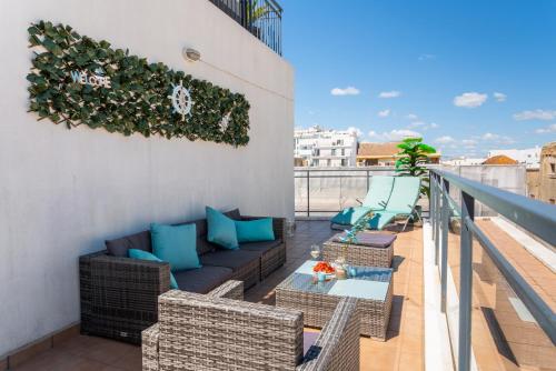 a patio with a couch and chairs on a balcony at Sunshine apartment by Ammonite&Cо in Olhão