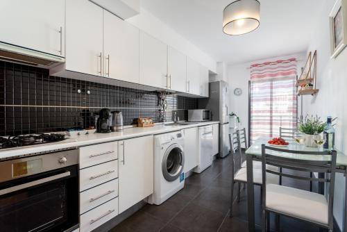 a kitchen with white cabinets and a washer and dryer at Sunshine apartment by Ammonite&Cо in Olhão