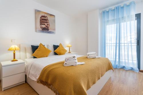 a white bedroom with a large bed with yellow pillows at Sunshine apartment by Ammonite&Cо in Olhão