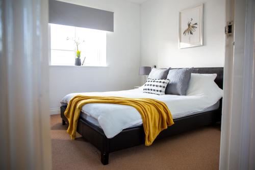 een slaapkamer met een bed met een gele deken erop bij Superb Apartment in Stratford upon Avon with Free Parking & Wi-Fi in Stratford-upon-Avon