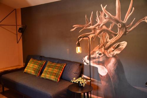 a painting of a deer on a wall next to a couch at Masonic Arms Gatehouse in Gatehouse of Fleet