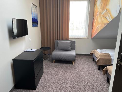 um quarto com uma cadeira, uma televisão e uma cama em Bursztynowa em Łuków