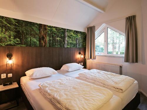a bedroom with two beds and a window with trees at Vakantiepark de Bosrand in Vaassen
