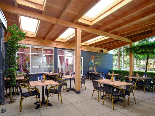 an outdoor patio with wooden tables and chairs at Vakantiepark de Bosrand in Vaassen