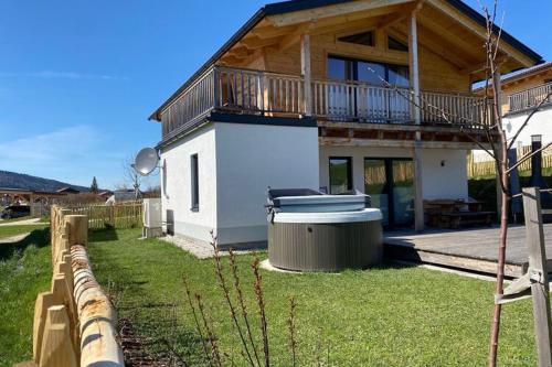 a house with a deck and a hot tub in the yard at Chalet Charivari Inzell, Inzell in Inzell
