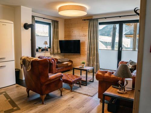 a living room with leather furniture and a flat screen tv at Chalet Charivari Inzell, Inzell in Inzell