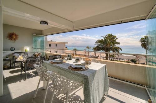 a table and chairs on a balcony with a view of the ocean at Cannes Luxury Rental - Stunning sea front apartment in Villeneuve-Loubet