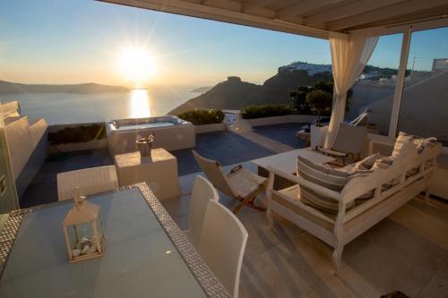 Sunset View Villa Santorini - with Outdoor Jacuzzi في فِروستيفاني: فناء مع طاولة وكراسي وإطلالة على المحيط