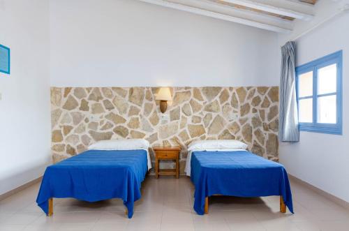2 łóżka w pokoju z kamienną ścianą w obiekcie Hostal Marina w Cala Ratjada