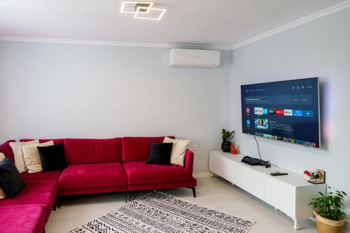 a living room with a red couch and a large screen at Loft Apartment with a great view of Ardino in Ardino