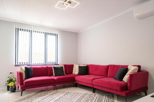 a red couch in a living room with windows at Cozy Apartment with a great view of Ardino in Ardino