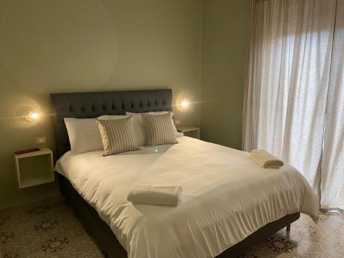 Schlafzimmer mit einem großen weißen Bett und einem Fenster in der Unterkunft DIMORE MORELLI in Amantea