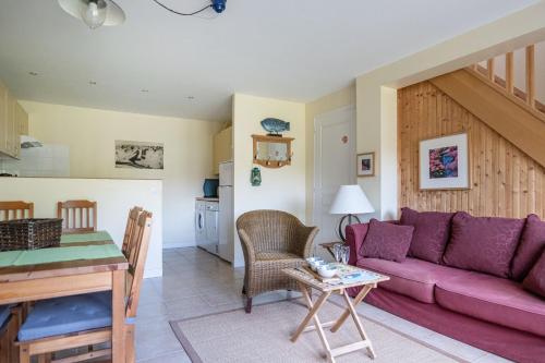 ein Wohnzimmer mit einem lila Sofa und einem Tisch in der Unterkunft Gîte Le Bisquin in Cancale
