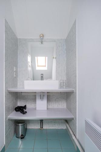 une salle de bain avec un lavabo et un miroir dans l'établissement Gîte Le Bisquin, à Cancale