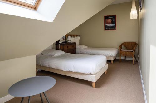 Schlafzimmer im Dachgeschoss mit 2 Betten und einem Tisch in der Unterkunft Gîte Le Bisquin in Cancale