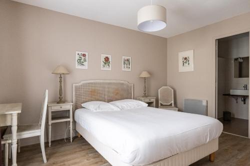 a bedroom with a white bed with two tables and two chairs at Gîte Taumain in Cancale