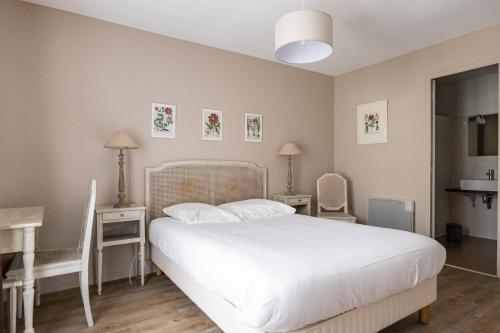 une chambre avec un lit blanc avec deux tables et deux chaises dans l'établissement Gîte Taumain, à Cancale