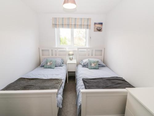 two beds in a small room with a window at Gerallt in Pwllheli