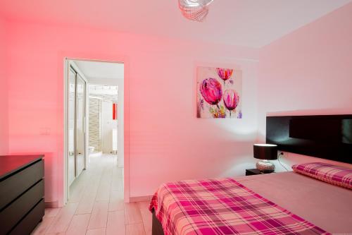 ein rosa Schlafzimmer mit einem Bett und einer rosa Wand in der Unterkunft Bungalow Costa Adeje Cortijo 1-8 in Playa de las Americas