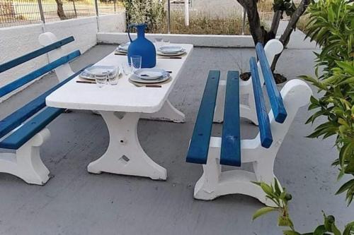 a white table with blue chairs and a blue vase at White Villa in Olive trees and Seaview to Panagia in Almiropótamos