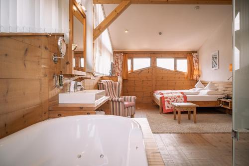 ein Bad mit einer Badewanne und ein Schlafzimmer in der Unterkunft Hotel Tirolerhof - Familotel Zugspitze in Ehrwald