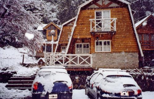 dos autos estacionados frente a una casa cubierta de nieve en Villa El Radal en San Martín de los Andes