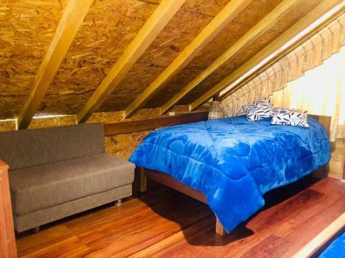 1 dormitorio con 1 cama azul y 1 sofá en Hospedaje Puntzán, en Baños