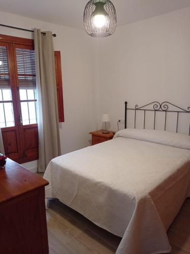 1 dormitorio con cama blanca y lámpara colgante en Fernan Caballero en Carmona