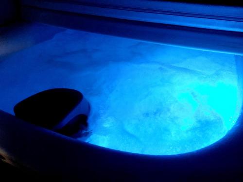 a person in a pool of blue water at Accanto Alle Mura Rooms & Relax Spa in Sirolo