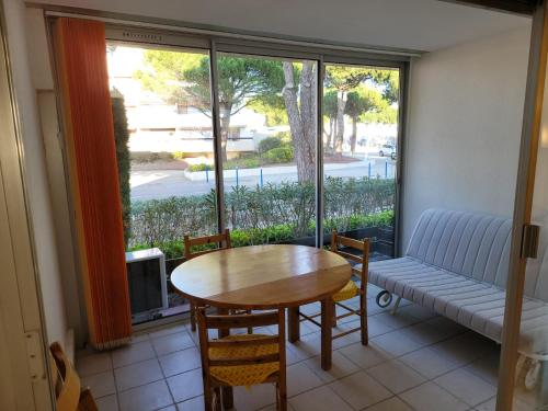 un salon avec une table, des chaises et un canapé dans l'établissement Studio avec loggia entre port, plage et piscine, au Grau-du-Roi