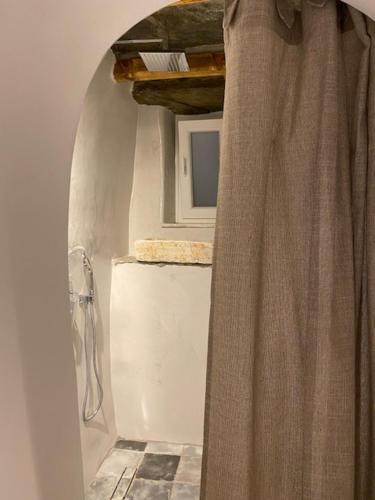 a bathroom with a shower curtain and a window at Serenity Living Platia, Tinos in Platiá