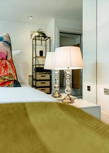 a bedroom with a bed and a table with a lamp at Riverside 2- Bedroom Apartments in London