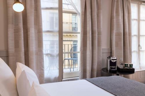 a bedroom with a bed and a large window at Hôtel Hélios Opéra in Paris