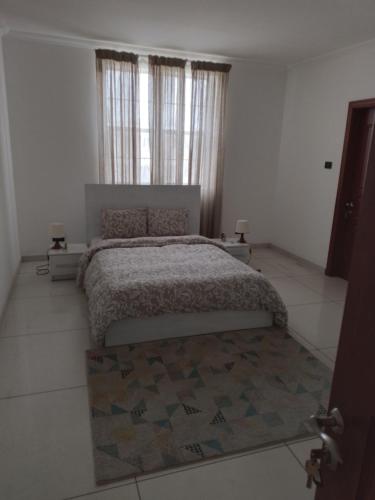 a bedroom with a bed and a window and a rug at Tricia's PLACE - One family at a time in Accra
