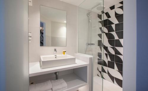 a white bathroom with a sink and a mirror at Hotel The Shepherd in Leuven
